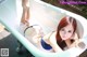 A woman in a blue bikini laying in a bathtub.