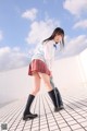 A woman in a school uniform is walking on a tiled floor.