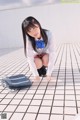 A young woman in a school uniform crouching on the ground.