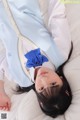 A woman laying on a bed with a blue bow on her head.