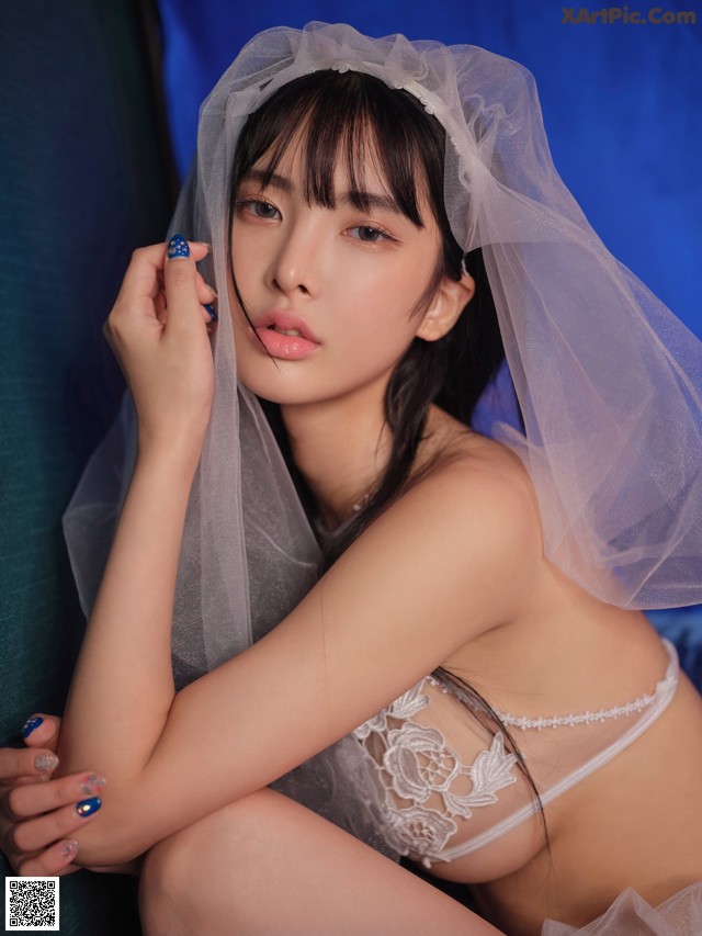 A woman in a white lingerie sitting on a blue couch.