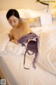 A woman laying on a bed holding a purple bra.