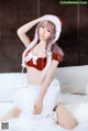 A woman in a santa outfit sitting on a bed.