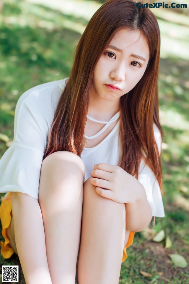 A woman sitting on the ground with her legs crossed.