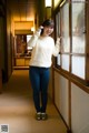 A woman standing in a hallway next to a window.