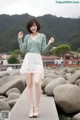 A woman in a green sweater and white skirt posing for a picture.