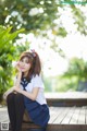 A woman in a school uniform sitting on a wooden bench.