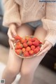 A woman holding a bowl of strawberries in her hands.