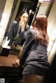 A woman in a business suit looking at herself in the mirror.