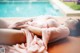 A woman laying on the ground next to a swimming pool.