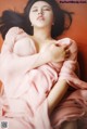 A woman in a pink dress laying on a couch.