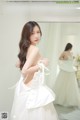 a woman in a white dress standing in front of a mirror