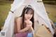 A young woman sitting in a tent with a basket of fruit.