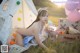 A naked woman sitting in front of a teepee with balloons.