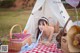 A woman laying on a picnic blanket next to a tent.