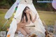 A naked woman sitting in a tent with a guitar.