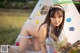 A young woman sitting in front of a teepee with a guitar.