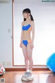 A woman in a blue and orange bikini standing on a scale.