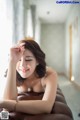 A woman laying on top of a brown couch.