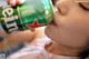 A little girl drinking from a can of heineken.