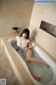 A woman sitting in a bathtub with her feet in the water.