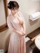 A woman in a pink robe standing in a bathroom.