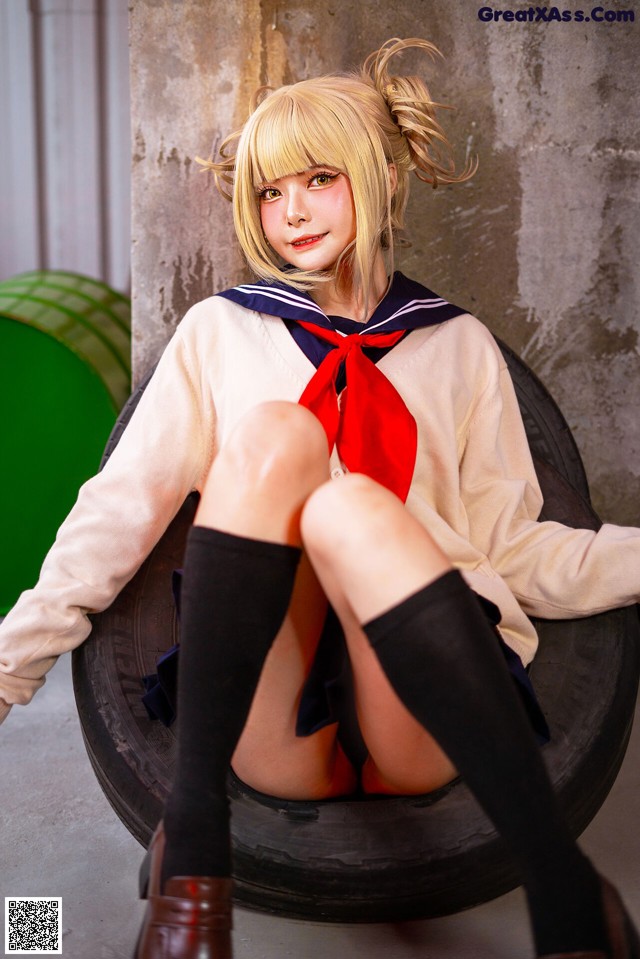 A woman in a sailor outfit sitting on a tire.