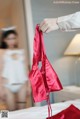 A person holding a red bra in front of a mirror.